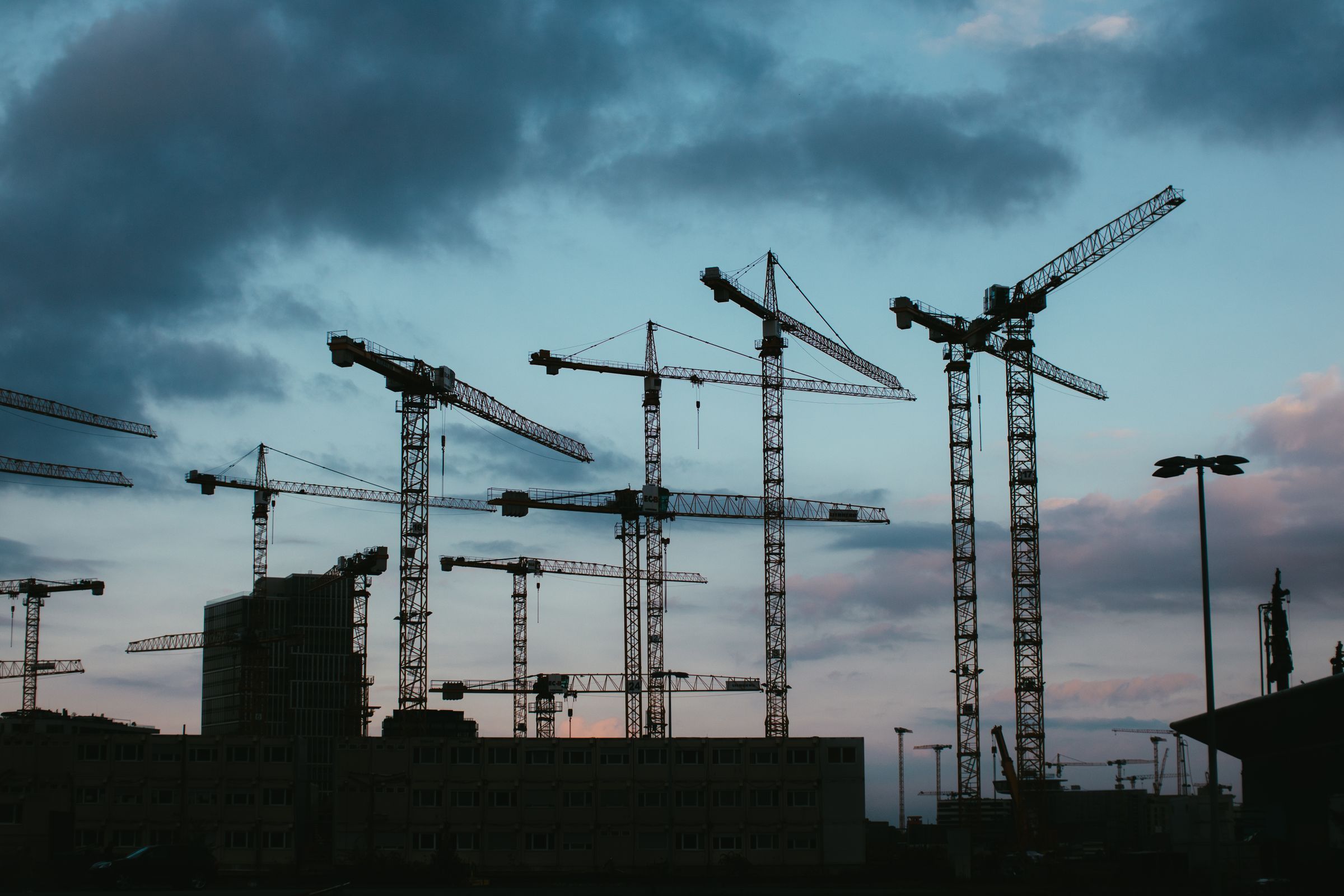 Tower cranes in silhouette against an evening sky